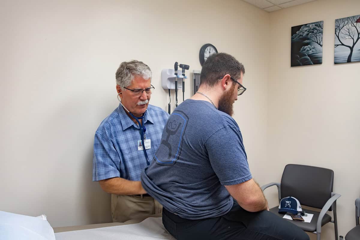 A patient receiving a medical examination from a healthcare professional in a clinic room.
