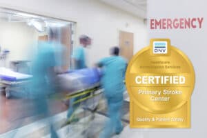 Medical team transporting a patient in an emergency room with DNV certification badge.