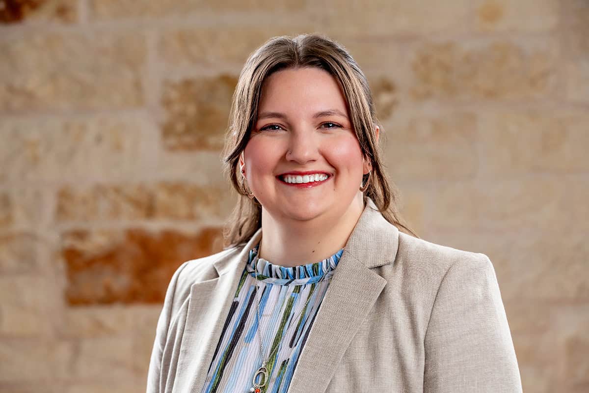 Portrait of Dr. Emmalie Berkovsky smiling in professional attire against a brick wall.