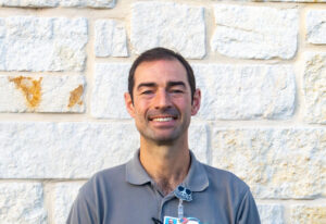 Peterson Health caregiver standing outdoors in front of a stone wall, smiling.