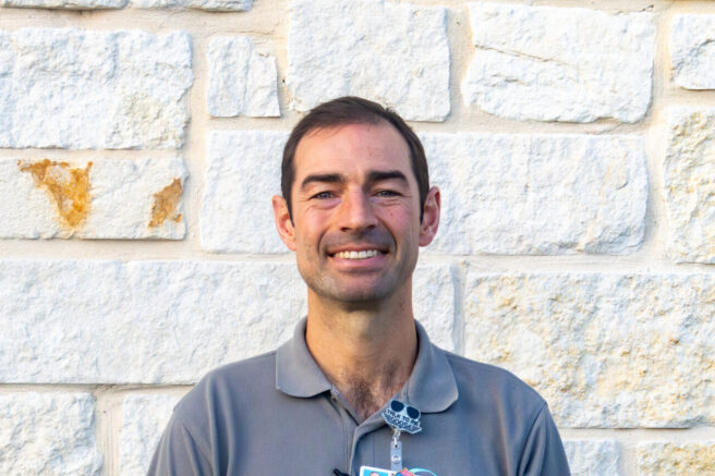 Peterson Health caregiver standing outdoors in front of a stone wall, smiling.